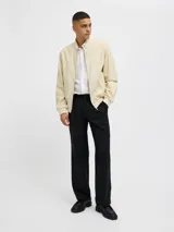 Campera bomber color beige de tejido liviano de lino y algodón, con cuello tipo baseball, mangas largas con puños de canalé, cierre con cremallera y bolsillos delanteros.