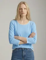 Remera de modal color blanco, con cuello redondo y mangas 3/4. Presenta un aplique bordado en color tostado en el cuello, los puños y el ruedo.
