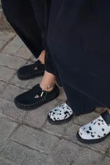 Zapato tipo zueco de cuero color beige, con diseño tejido artesanal en todo el contorno y ajuste mediante correa con hebilla metálica en el empeine.