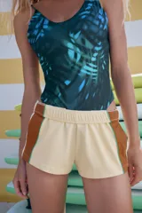 Shorts mini color beige claro, con cintura elástica de tiro medio y bandas laterales marrones con ribete verde.