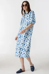 Vestido midi de lino con estampado floral azul y blanco, cuello clásico, mangas abullonadas hasta el codo y cierre frontal con botones de nácar.