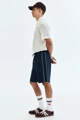 Short azul marino de punto con leve brillo, cintura elástica con cordón de ajuste y ribetes laterales en color blanco.