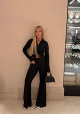 Conjunto negro compuesto por un top de manga larga con cierre frontal y abertura tipo cut-out, y un pantalón de corte acampanado. Confeccionado en tela elástica que se ajusta al cuerpo.