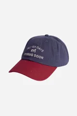 Gorra azul con visera bordó, con logo y texto bordados en relieve en el frente.