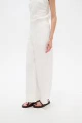 Pantalón blanco de viscosa, de corte ancho y tiro alto, con bolsillos laterales.