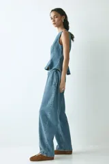 Pantalón oversized en denim de algodón rígido, con elástico revestido en la cintura, cierre con botón y bolsillos laterales discretos. Presenta un corte con piernas de diseño curvo y volumen.