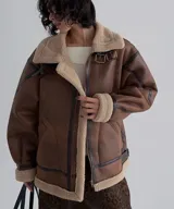 Campera tipo gamulán de cuero sintético en color marrón, con interior y detalles en corderito beige. Presenta cierre frontal, cuello con solapas, puños ajustables y correas decorativas con hebillas metálicas.