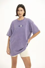 Remera lila con estampa de palmera y texto en el pecho, corte holgado y mangas cortas.