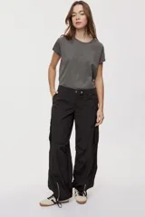 Pantalón cargo negro de corte relajado y pierna ancha con bolsillos laterales con solapa, cintura con doble broche y cierres metálicos en los tobillos.