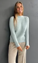 Sweater de punto con textura suave, color celeste, con diseño de ochos en el frente y tejido morley en mangas y espalda. Presenta cuello redondo a la base y mangas largas.