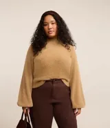 Suéter color beige de punto con textura de pelitos, cuello alto y mangas largas.