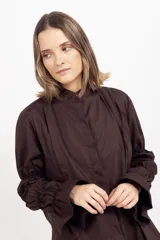Camisa blanca de algodón con cuello mao, cierre frontal oculto y mangas largas fruncidas con volumen.