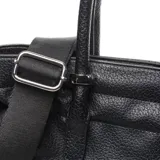 Cartera grande de símil cuero color negro, tipo tote bag, con doble asa de mano y correa larga de tela ajustable. Cuenta con detalles de cordones con nudos en los laterales y el logo metálico de la marca en la parte frontal.