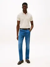 Chomba Tommy Hilfiger color crema con estampado de hojas en tono beige, cuello clásico, solapa de dos botones, corte regular y logo bordado en el pecho.