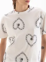 Remera de algodón pima blanco con estampado de corazones formados por cadenas, de calce regular, mangas murciélago y cuello redondo.