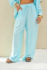 Pantalón celeste de corte holgado y pernera ancha, con cintura elástica fruncida y cordón ajustable del mismo tono.