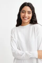 Vestido tipo sweater color blanco, de corte recto y largo hasta la rodilla, con cuello redondo y mangas largas.