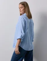 Camisa de lino color beige de la marca Dash, con cuello camisero, cierre frontal con botones, manga larga regulable con presilla y un bolsillo aplicado en el pecho.