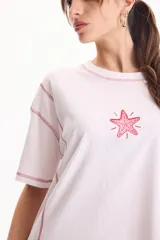 Remera de algodón blanca de manga corta y corte semi boxy, con costuras a contratono en color rosado, detalles de cortes y bordado de estrella de mar en el frente.