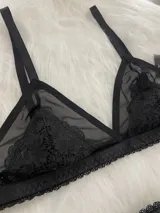 Conjunto de lencería compuesto por un corpiño triangular de microtul transparente con detalles de encaje en las copas y una tanga regulable con elástico ancho.