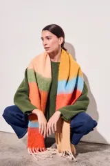 Bufanda larga tejida a rayas horizontales en tonos naranja, celeste, amarillo y beige, con flecos en los extremos.