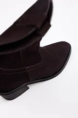 Bota de caña media estilo western, confeccionada en cuero vacuno con acabado de gamuza en color marrón, con taco cuadrado y puntera redondeada.