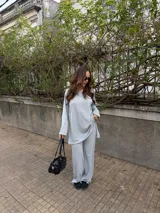 Conjunto de dos piezas de lanilla en color gris melange, compuesto por un buzo holgado de manga larga con cuello redondo y un pantalón largo de corte recto y holgado.