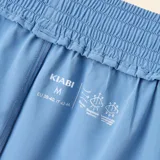 Short deportivo de corte holgado en color azul con paneles laterales en color crema. Presenta cintura elástica con cordón de ajuste y aberturas laterales.