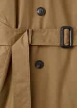 Trench coat de algodón en color verde oliva, con diseño largo y oversize. Presenta cuello camisero de pana, cierre de doble botonadura, cinturón con hebilla, trabillas en hombros y puños ajustables.