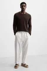 Sandalia plana color beige, estilo 'dos tiras' con hebillas ajustables en el empeine. La suela tiene un borde forrado en yute trenzado.