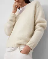 Jersey de punto para mujer, color rojo oscuro, con cuello en V y manga larga. Presenta un acabado afelpado y holgado, con remates en canalé.