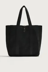 Bolso tipo shopper de algodón color negro, con asas superiores y tira de cuero con botón metálico para el cierre. Diseño amplio y versátil para uso diario.