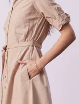 Vestido camisero blanco de algodón con cuello con solapa, delantera abotonada, mangas 3/4 regulables con presilla y botón, y cintura con lazo de ajuste.