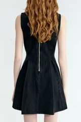 Vestido corto sin mangas en denim negro, con escote redondo, cuerpo entallado y falda acampanada con pliegues.