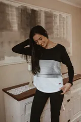 Remera de manga larga con diseño tricolor, combinando bloques de color negro, rayas horizontales y blanco. Presenta un corte holgado y funcional, ideal para maternidad y lactancia.
