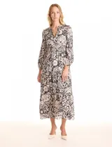 Vestido maxi de gasa estampada en blanco y negro, marca Julia Jordan. Escote en V, hombros con fruncidos, mangas largas amplias con puños elastizados. Cintura con faja ancha de punto smock y falda escalonada con vuelo. Cierre invisible y botones metálicos en la espalda. Forro interno a tono.