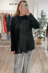Sweater de punto negro con diseño de trenzas verticales, cuello redondo y corte holgado con aberturas laterales en el ruedo.