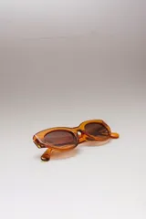 Lentes de sol ovalados con montura de acetato color naranja y lentes marrones degradados. Ofrecen protección UVA/UVB.