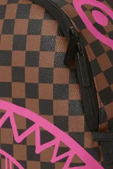 Mochila Sprayground de ecopiel con diseño a cuadros en tonos marrón y negro, y estampado de boca de tiburón rosa con efecto dripping.