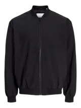 Campera bomber negra Jack & Jones de tejido plano liviano, con cuello baseball, cierre frontal de cremallera, bolsillos delanteros y puños de canalé. Confeccionada en poliéster y poliéster reciclado.