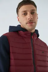 Chaleco puffer verde oliva con cierre frontal y bolsillos laterales con cierre. Interior forrado en color naranja.