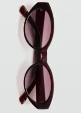 Lentes de sol con montura ovalada de pasta color bordó y cristales degradados.