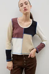 Remera de manga larga con diseño de bloques de color en tonos neutros, confeccionada con costuras externas visibles en color azul contrastante.