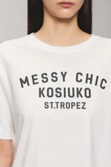 Remera Kosiuko de algodón color blanco, de corte regular y mangas cortas hasta el codo. Cuenta con un diseño estampado en el frente con la leyenda "Messy Chic Kosiuko St. Tropez".