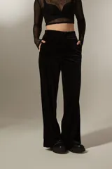 Pantalon de corte recto y tiro alto, confeccionado en tela de terciopelo negro con costuras verticales decorativas en el frente.