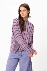 Sweater de punto con diseño de rayas verticales en relieve y textura trenzada, color terracota y beige. Presenta cuello redondo, corte holgado y diseño cropped.