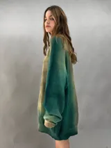 Buzo tejido de lana merino con diseño oversize, manga ranglan y cuello levemente elevado. Presenta un efecto de teñido degradado que combina tonos verdes y beige.