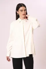 Camisa blanca de corte oversize, con cuello clásico y mangas largas con puños abotonados.