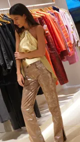 Pantalón de cuero color marrón con estampado abstracto, corte acampanado y abertura en el ruedo.