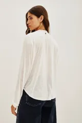 Camisa de algodón y viscosa color blanco, con mangas largas y diseño frontal con bordados geométricos y florales en contraste negro. Presenta cuello redondo con pequeña abertura y cierre frontal de botones.